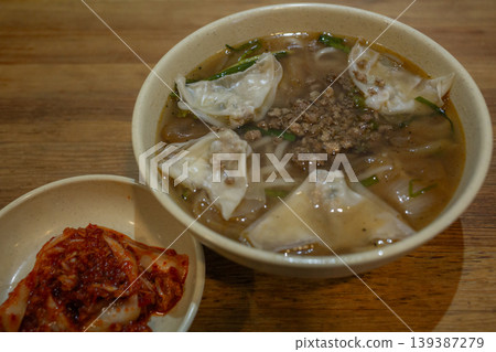 [South Korea] Wonton soup and kimchi served in a bowl at a dumpling restaurant in Myeongdong, Seoul, the capital city. 139387279