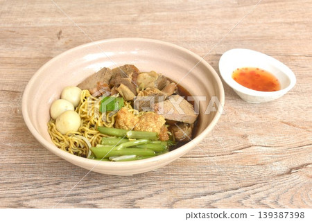 Chinese egg noodles topping braised pork and meatball in brown soup on bowl dipping spicy sour chili sauce 139387398