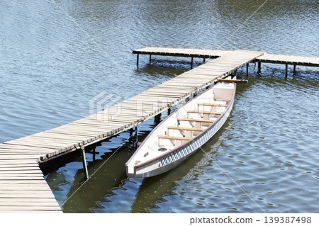 An old white boat near a wooden bridge. Summer landscape. An old white boat near a wooden bridge. Summer landscape. 139387498