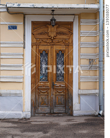 Close-up of an intricate classic entrance door on a city street. The facade of the historical building features luxurious wood carvings, decorative metal details, and elegant architectural ornaments. Close-up of an intricate classic entrance door on a city street. The facade of the historical building features luxurious wood carvings, decorative metal details, and elegant architectural ornaments. 139388077