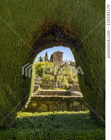 Historic Stone Tower Seen Through Garden Archway In Lush Walled Garden With Cypress Trees Historic Stone Tower Seen Through Garden Archway In Lush Walled Garden With Cypress Trees 139388170