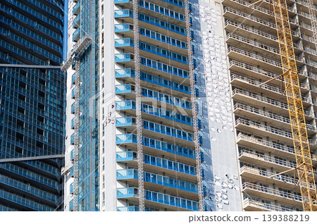 A high-rise building under construction with a tower crane and glass balconies. A high-rise building under construction with a tower crane and glass balconies. 139388219