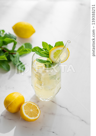 Refreshing lemon mint drink with ice in glass, homemade summer lemonade on marble background Refreshing lemon mint drink with ice in glass, homemade summer lemonade on marble background 139388251