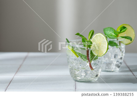 A fresh mojito with lime, mint and ice in glasses. Citrus lemonade or cocktail on a table A fresh mojito with lime, mint and ice in glasses. Citrus lemonade or cocktail on a table 139388255