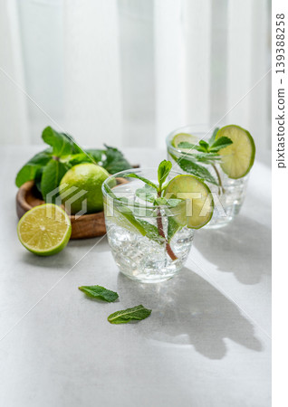 A fresh mojito with lime, mint and ice in glasses. Citrus lemonade or cocktail on a concrete table A fresh mojito with lime, mint and ice in glasses. Citrus lemonade or cocktail on a concrete table 139388258