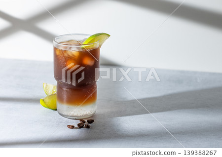 Cold Coffee Tonic Drink With Lime and Ice on light background with shadows Cold Coffee Tonic Drink With Lime and Ice on light background with shadows 139388267