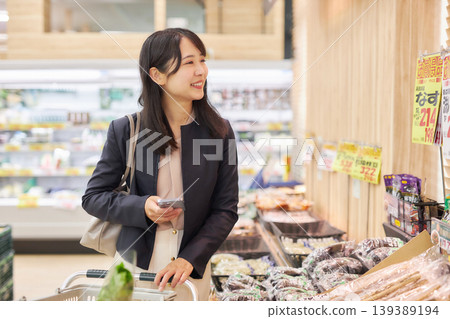 A young woman shopping at a supermarket on her way home from work. A young woman shopping at a supermarket on her way home from work. 139389194