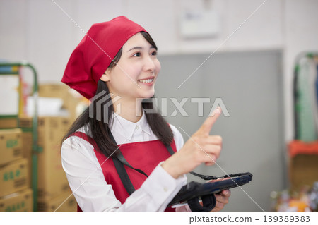 A young woman manages inventory using a tablet in the back room. 139389383