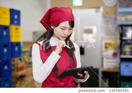 一位年輕女子在後屋使用平板電腦管理庫存。 139389385