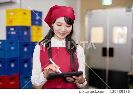 A young woman manages inventory using a tablet in the back room. A young woman manages inventory using a tablet in the back room. 139389386