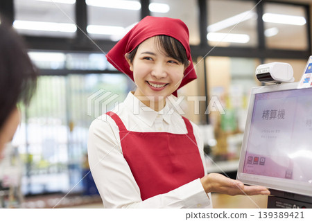 A young woman working at the checkout counter of a supermarket A young woman working at the checkout counter of a supermarket 139389421