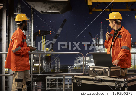 Offshore male worker uses walkie talkie to manage drilling rig operations at sea, ensuring correct and efficient petroleum extraction. Fuel production in the oil and gas industry. Offshore male worker uses walkie talkie to manage drilling rig operations at sea, ensuring correct and efficient petroleum extraction. Fuel production in the oil and gas industry. 139390275
