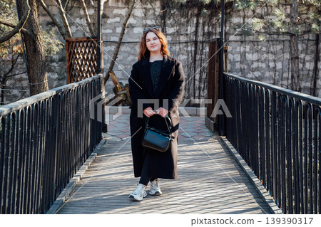 Young caucasian woman standing on wooden bridge holding handbag in park setting. Lifestyle and outdoor portrait Young caucasian woman standing on wooden bridge holding handbag in park setting. Lifestyle and outdoor portrait 139390317
