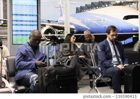 Waiting for flight, chatting and woman with man inside airport interior passing time. Getting acquainted, waiting for plane and girl with African traveler sharing stories about their planned holidays 139390413