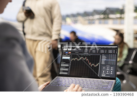 Digital nomad woman analyzing financial trends and stock market data on laptop in airport terminal lounge, waiting for flight boarding. Reviewing candlestick charts and forex exchange rates. Digital nomad woman analyzing financial trends and stock market data on laptop in airport terminal lounge, waiting for flight boarding. Reviewing candlestick charts and forex exchange rates. 139390468