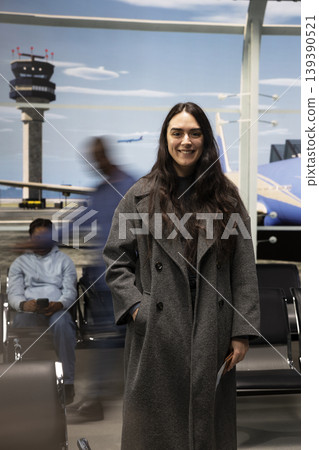 Portrait of joyful woman in airport traveling to dream destination, fast paced motion blur people in background. Upbeat girl excited about holiday trip next to hectic crowd, busy lifestyle concept Portrait of joyful woman in airport traveling to dream destination, fast paced motion blur people in background. Upbeat girl excited about holiday trip next to hectic crowd, busy lifestyle concept 139390521
