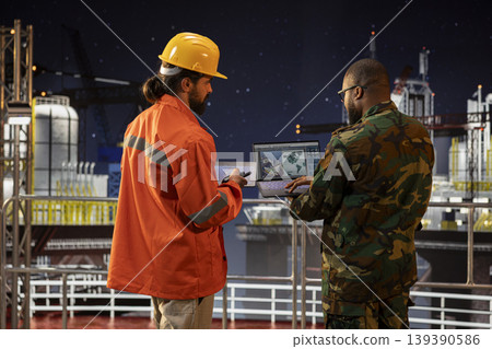 Military naval unit stationed on offshore platform for border security using laptop program. Army soldier safeguarding drilling rig operations, looking at international waters map on notebook Military naval unit stationed on offshore platform for border security using laptop program. Army soldier safeguarding drilling rig operations, looking at international waters map on notebook 139390586