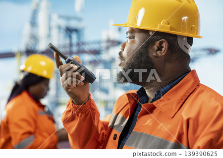 Closeup of fossil fuel company manager on drilling barge uses walkie talkie to ensure uninterrupted communication with workers. Man on offshore rig platform transmits instructions through radio device 139390625