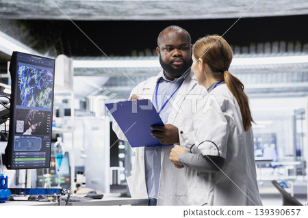 Diverse scientists team monitoring chemical reaction of molecules on tv screen and lab records, working on RD strategy in laboratory and microbiology clinical study on patient. Diverse scientists team monitoring chemical reaction of molecules on tv screen and lab records, working on RD strategy in laboratory and microbiology clinical study on patient. 139390657