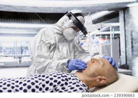 Researcher in protective gear works in biohazard zone to treat a contagious patient, analyzing infection data to advance immunology and epidemic prevention in biotechnology research. Researcher in protective gear works in biohazard zone to treat a contagious patient, analyzing infection data to advance immunology and epidemic prevention in biotechnology research. 139390663