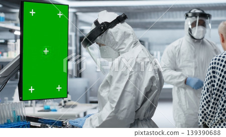 Vertical chroma key screen next to scientist in a biohazard facility treats a patient with infectious disease symptoms, study contamination control and vaccination methods for protection. Camera B. Vertical chroma key screen next to scientist in a biohazard facility treats a patient with infectious disease symptoms, study contamination control and vaccination methods for protection. Camera B. 139390688