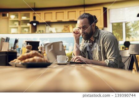 Confused disoriented man being uncertain about task completion, frowning at laptop screen while he works from home. Ambiguous misunderstanding information and person in doubt. 139390744