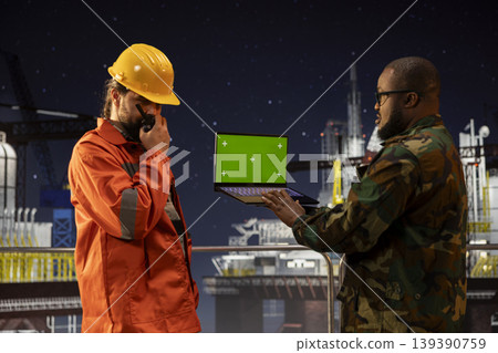 Green screen laptop used by military unit on offshore platform for counter terrorism security. Army soldier safeguarding drilling rig operations using chroma key notebook Green screen laptop used by military unit on offshore platform for counter terrorism security. Army soldier safeguarding drilling rig operations using chroma key notebook 139390759