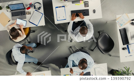 Top down view of diverse colleagues working in modern office, focusing on project planning, performance metrics and report sharing. Business people review data for forecasting. Top down view of diverse colleagues working in modern office, focusing on project planning, performance metrics and report sharing. Business people review data for forecasting. 139390792