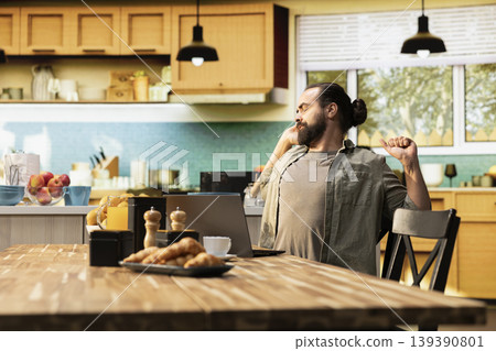 Male freelancer stretching his back muscles with arms up at home, discomfort due to bad chair posture. Experiencing lower back and neck stiffness, burnout and physical fatigue during remote work. Male freelancer stretching his back muscles with arms up at home, discomfort due to bad chair posture. Experiencing lower back and neck stiffness, burnout and physical fatigue during remote work. 139390801