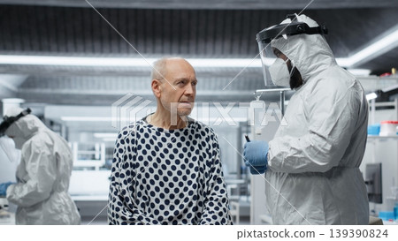 Male medic scientist treating patient with severe infection symptoms, using immunology testing in a containment lab to support vaccine development and epidemic control. Camera B. Male medic scientist treating patient with severe infection symptoms, using immunology testing in a containment lab to support vaccine development and epidemic control. Camera B. 139390824