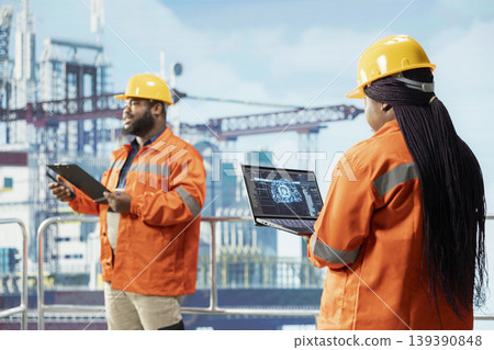 Offshore platform experts evaluate AI machine learning metrics on laptop to refine operational efficiency. Ship crew using artificial intelligence technology to monitor drilling production activities Offshore platform experts evaluate AI machine learning metrics on laptop to refine operational efficiency. Ship crew using artificial intelligence technology to monitor drilling production activities 139390848