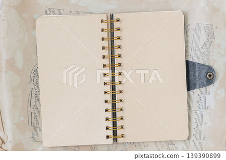 Flat lay of open notebook with spiral binding lies on sheet music, with blank pages ready for notebook layout, writing, journaling, study, or planner mockup. Concept of education, music, design 139390899