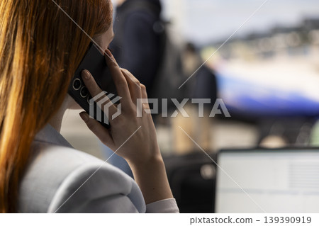 Businesswoman transmitting KPIs insights via phone call in airport lounge, checking financial data for monthly reports. Advisor does budgeting and accounting during air travel, global mobility. Businesswoman transmitting KPIs insights via phone call in airport lounge, checking financial data for monthly reports. Advisor does budgeting and accounting during air travel, global mobility. 139390919