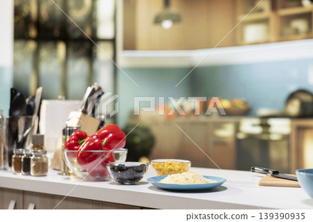 Empty kitchen island arranged with pizza essentials such as corn, mozzarella, red bell pepper and olives. Baking tools and utensils on countertop reflecting home cooking vibe on the weekend. Empty kitchen island arranged with pizza essentials such as corn, mozzarella, red bell pepper and olives. Baking tools and utensils on countertop reflecting home cooking vibe on the weekend. 139390935