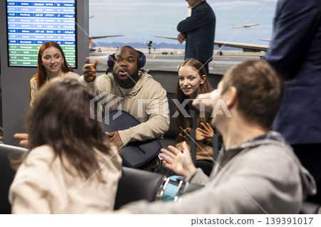 Chatting, diversity and group of friends inside busy airport lounge. Doing conversation, long flight layover and multiethnic passengers sitting on chairs in transit hub before departure Chatting, diversity and group of friends inside busy airport lounge. Doing conversation, long flight layover and multiethnic passengers sitting on chairs in transit hub before departure 139391017