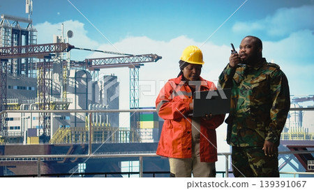 Soldier working on offshore platform issuing command over radio transmission. Military unit boarding drilling barge under maritime interdiction protocol, monitoring perimeter, 139391067