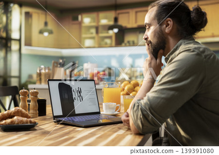 Casual man looking at new phone product announcement on laptop, interest and curiosity for new technology on mobile gadget. High tech release coming soon, innovative technology news. 139391080