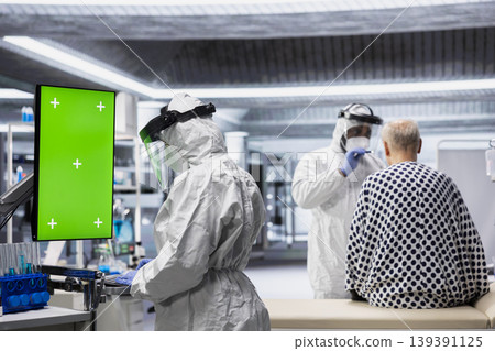 Medic looks at vertical green screen on monitor and observes patient reactions to antiviral treatment in a controlled laboratory setting. Vaccine development progress in prevention center. Medic looks at vertical green screen on monitor and observes patient reactions to antiviral treatment in a controlled laboratory setting. Vaccine development progress in prevention center. 139391125