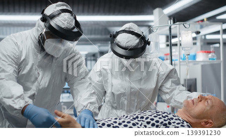 Doctors in hazmat suit doing examination on a patient with viral symptoms, analyzing medical data and testing vaccines to ensure health safety and improve global pandemic response. Camera B. Doctors in hazmat suit doing examination on a patient with viral symptoms, analyzing medical data and testing vaccines to ensure health safety and improve global pandemic response. Camera B. 139391230
