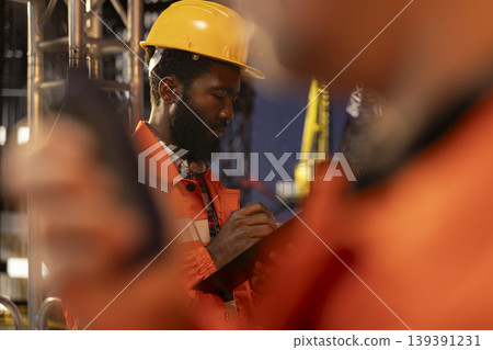 Industrial worker monitoring offshore drilling rig operation with tablet, focusing on professional fossil fuels and oil extraction on a platform. Natural gas and petrol for the oil industry. Industrial worker monitoring offshore drilling rig operation with tablet, focusing on professional fossil fuels and oil extraction on a platform. Natural gas and petrol for the oil industry. 139391231