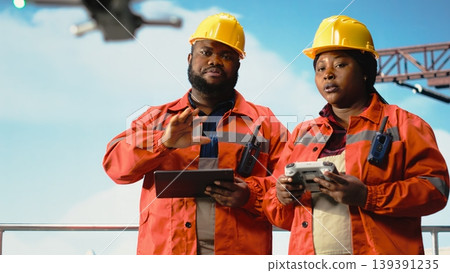 Offshore platform professionals working together, using drone for site inspections. Teamworking colleagues use aerial photography technology to determine optimal locations for drilling pads 139391235