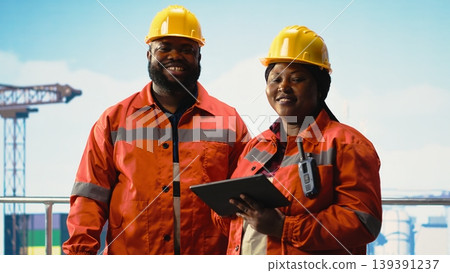 Happy offshore platform engineering team monitoring operations on oil production barge. Joyous drilling rig ship crew wearing safety gear reviewing energy operations Happy offshore platform engineering team monitoring operations on oil production barge. Joyous drilling rig ship crew wearing safety gear reviewing energy operations 139391237