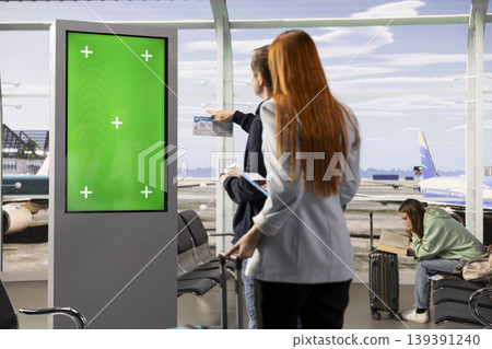 Green screen large board with multiethnic travelers in airport terminal, surrounded by passengers, luggage and departure activity. Waiting for boarding plane, air travel concept. Green screen large board with multiethnic travelers in airport terminal, surrounded by passengers, luggage and departure activity. Waiting for boarding plane, air travel concept. 139391240