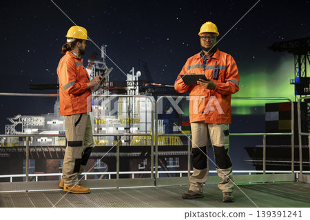 Portrait of offshore platform worker monitoring anomaly detection under green arctic lights. African american man on drilling ship using tablet to control subsea systems during aurora borealis 139391241