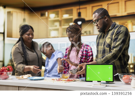 Chroma key next to African American family cooking during pizza day and layering toppings. Culinary activity highlights home cooking, family fun and the joy of tasty homemade food. Chroma key next to African American family cooking during pizza day and layering toppings. Culinary activity highlights home cooking, family fun and the joy of tasty homemade food. 139391256