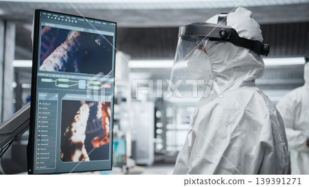 Doctor in quarantine performing clinical study on an infectious patient, testing vaccine responses and monitoring DNA molecules on monitor to develop treatments for epidemics. Camera A. Doctor in quarantine performing clinical study on an infectious patient, testing vaccine responses and monitoring DNA molecules on monitor to develop treatments for epidemics. Camera A. 139391271