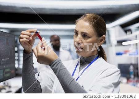Female scientist examines blood sample in a test tube in medical laboratory, analyzing data for vaccine study and monitoring chemical reactions to support healthcare innovation and research. Female scientist examines blood sample in a test tube in medical laboratory, analyzing data for vaccine study and monitoring chemical reactions to support healthcare innovation and research. 139391368