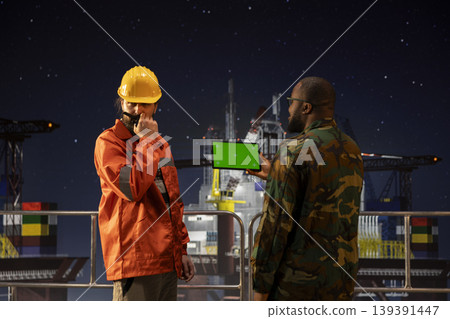 Isolated screen tablet used by soldier protecting strategic national energy assets on drilling barge. Military unit on offshore platform deck perimeter to deter hostile actions using chroma key device Isolated screen tablet used by soldier protecting strategic national energy assets on drilling barge. Military unit on offshore platform deck perimeter to deter hostile actions using chroma key device 139391447