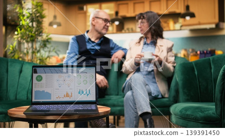 Computer app managing clean renewable energy at home for elderly couple, green innovation with photovoltaic panels and energy efficiency reflecting eco-friendly household in retirement. Computer app managing clean renewable energy at home for elderly couple, green innovation with photovoltaic panels and energy efficiency reflecting eco-friendly household in retirement. 139391450