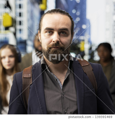 Portrait of businessman with a backpack standing on the sidewalk in city center, walking across metropolitan area business district. Male professional on a busy crowded street. Portrait of businessman with a backpack standing on the sidewalk in city center, walking across metropolitan area business district. Male professional on a busy crowded street. 139391469